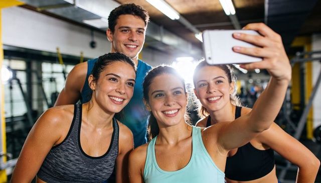 Smiling friends taking post-workout selfie at gym showing teamwork and fitness