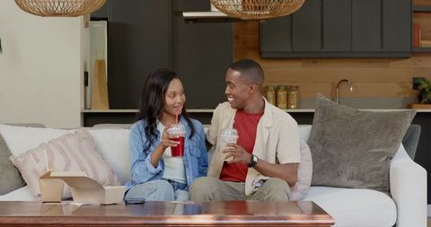 Couple Enjoys Relaxing Time at Home with Refreshing Drinks on Couch