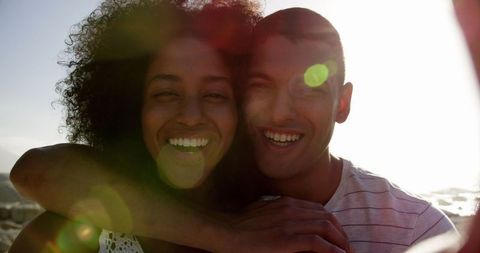 Joyful Biracial Couple Embracing on Sunlit Beach