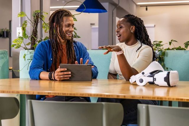 African American Coworkers Collaborating Over Tablet With VR Headset in Modern Workspace