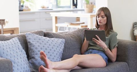 relaxed middle-aged woman browsing on tablet at home - Download Free Stock Images Pikwizard.com
