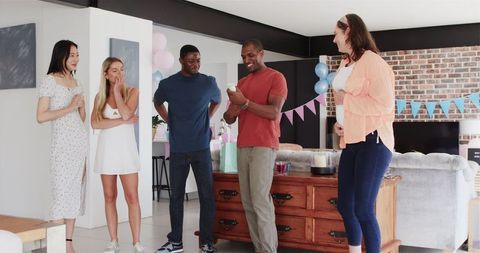 Group of Friends Celebrating with Confetti at Cheerful Baby Shower
