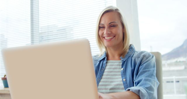 Smiling Woman Working on Laptop in Bright Office Environment - Download Free Stock Images Pikwizard.com