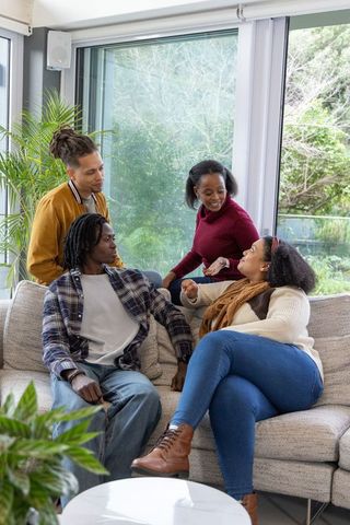 African american friends chatting on sectional sofa in sunlit modern living room