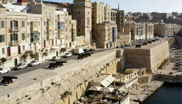 Sunlit mediterranean bastion with historic cannons overlooking limestone seaside quay