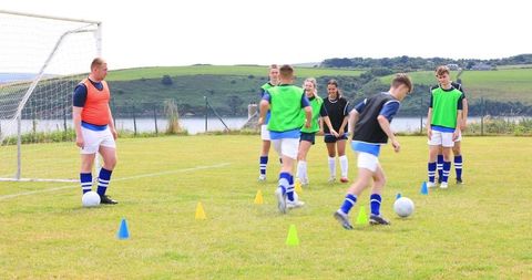 Youth soccer team practicing passing drills on scenic lakeside field