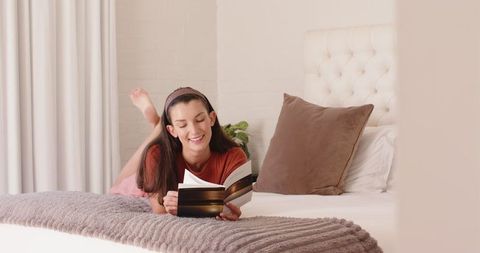 Mid Adult Woman Enjoying a Paperback Book in Comforting Bedroom