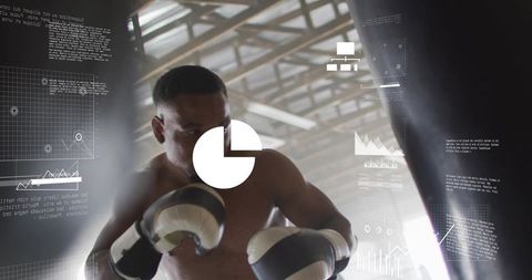 Boxer training shirtless wearing padded gloves punching heavy bag at warehouse with hud overlays