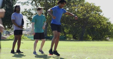 Diverse friends practicing agility drills on park field for fitness and teamwork