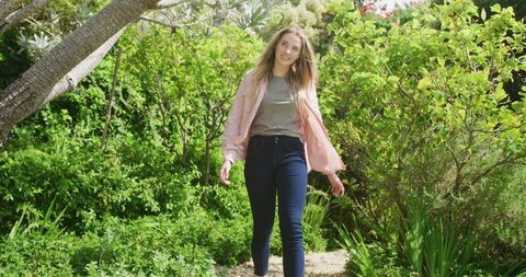 Happy Woman Strolling Through Lush Garden on Sunny Day