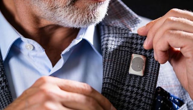 Senior executive adjusting fingerprint lapel pin on houndstooth blazer for meeting