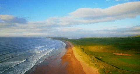 Transparent waves lapping pristine sandy beach under partly cloudy sky
