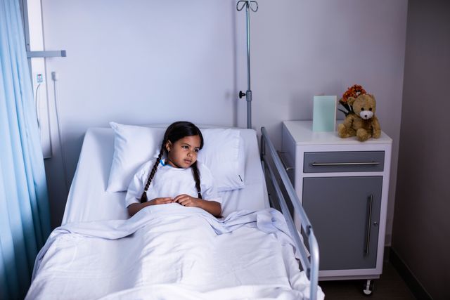 Young girl lying in a hospital bed, looking thoughtful. Ideal for use in healthcare, medical, and pediatric care contexts. Can be used in articles about child healthcare, hospital stays, and recovery processes.