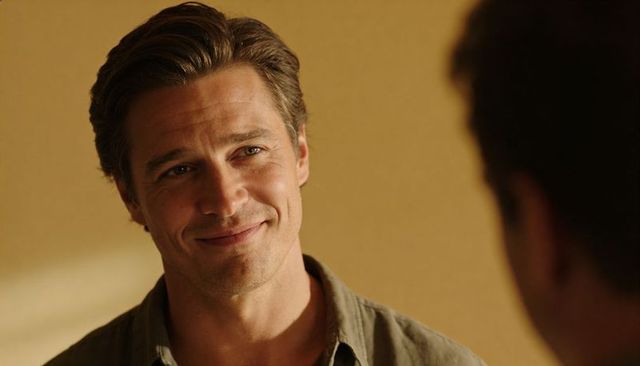Warm smiling man leaning forward in olive shirt during candid conversation, closeup portrait