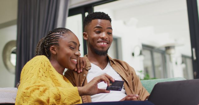 Happy african american couple sitting on sofa and making online shopping - Download Free Stock Photos Pikwizard.com