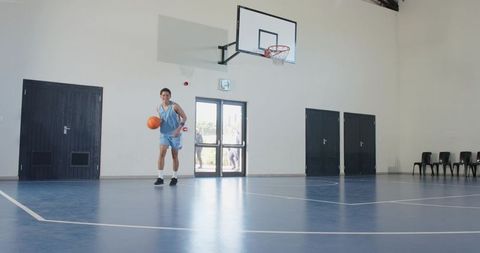 Asian athlete dribbling basketball on indoor court in gymnasium
