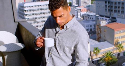Urban professional with coffee on modern high-rise balcony