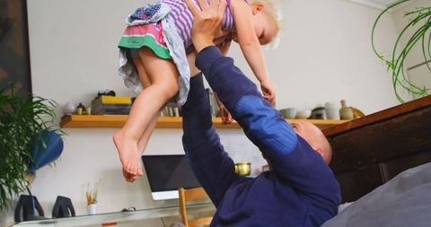 Joyful Father Lifting Young Daughter in Living Room Scene