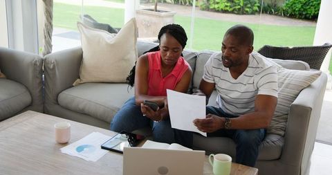 Couple reviewing finances at home on couch