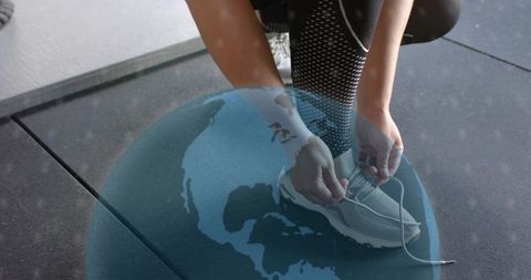 Woman tying running shoe laces in mesh leggings with globe overlay for global fitness