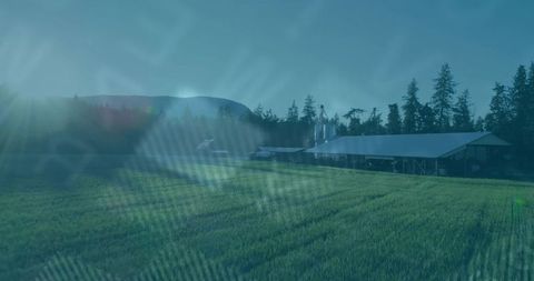 Rustic barn with silos by green field and rolling hills and pines