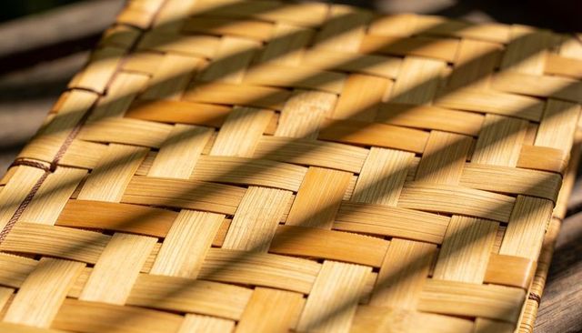 Sunlit woven bamboo placemat with stitched edge and diagonal shadow pattern