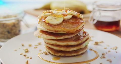 Stack of fluffy pancakes with banana and maple syrup