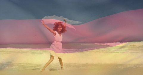 Woman walking along beach with flowing scarf and pastel translucent light overlay