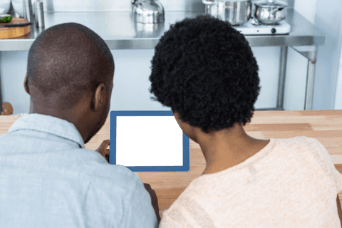 Transparent Rear View of Couple Viewing Digital Tablet in Kitchen