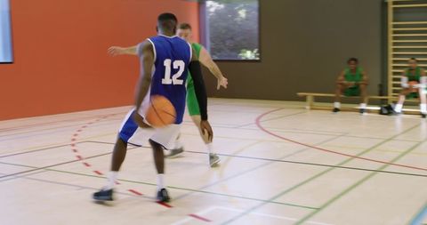 Diverse basketball players dribbling and defending on indoor gym court during action-packed game