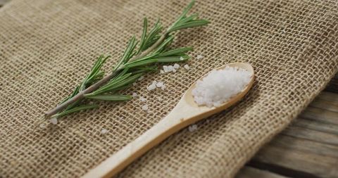 Fresh rosemary and salt on rustic burlap surface