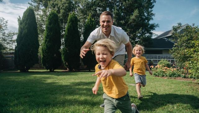 Father chasing laughing children running across backyard lawn playful family afternoon