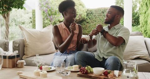 Joyful Couple Sharing Desserts and Laughs on Sunny Patio Retreat