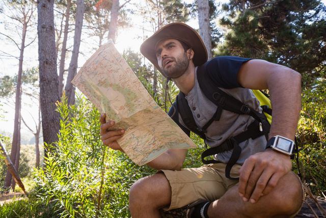 Man holding the map and looking at the distance in the forest
