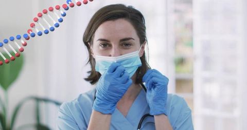 Clinician adjusting surgical mask in clinic wearing scrubs gloves stethoscope DNA helix
