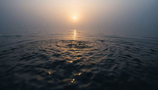 Sunrise ripple on misty ocean with golden reflection and tranquil concentric waves