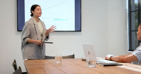 Businesswoman Presenting Graph Data to Colleague in Modern Office Meeting