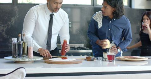 African american friends preparing homemade pizza in modern sunlit kitchen gathering