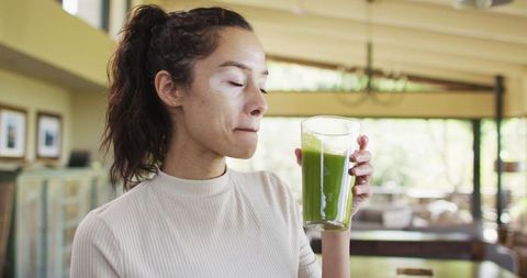 Woman with Vitiligo Drinking Green Smoothie in Cozy Home Kitchen