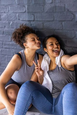 Friends taking gym selfie laughing and posing in athleisure after workout