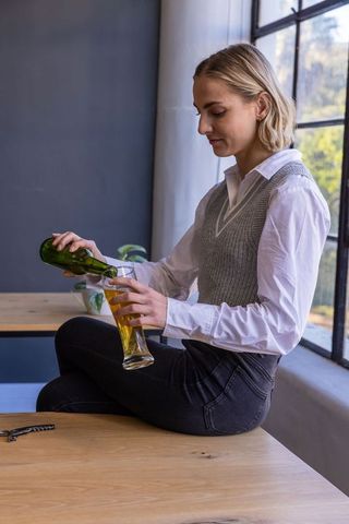 Casual Woman Relaxing with Cold Beer Near Sunlit Window