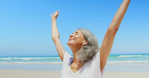 Joyful Elderly Woman Enjoying Sun on Peaceful Beach - Download Free Stock Images Pikwizard.com