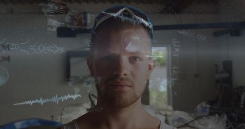Male technician wearing safety goggles with futuristic hud overlays in garage workshop