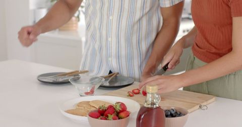 Couple Preparing Breakfast with Pancakes and Fresh Strawberries