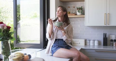 Middle-aged Woman Enjoys Meal in Bright Modern Kitchen Interior