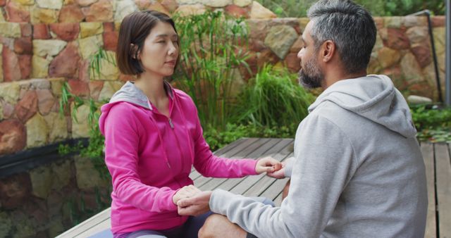 Couple sitting cross-legged, practicing Zen meditation in serene garden. Suitable for topics on mindfulness, wellness, and relationship bonding, highlighting healthy lifestyle and tranquility benefits.