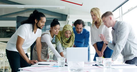Diverse Professionals Collaborating Around Laptop in Modern Office