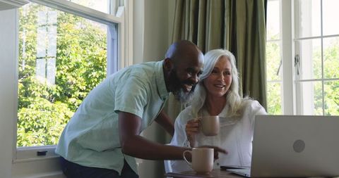 Smiling Couple Bonding Over Coffee and Laptop at Home