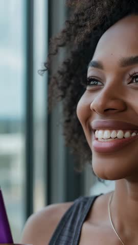 Vertical video: Woman smiling and gazing out window, urban calm and hopeful portrait