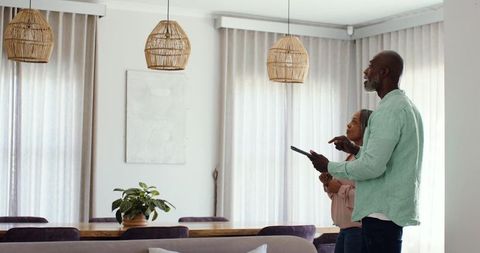 Diverse mature couple planning home update holding tablet in cozy neutral dining space